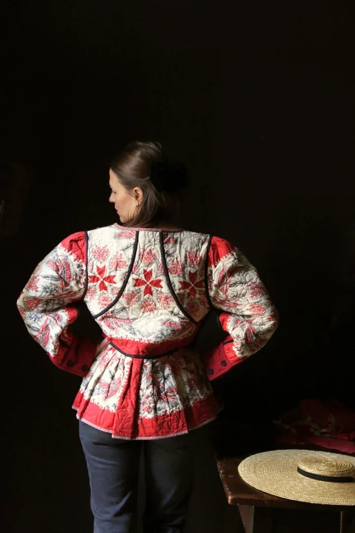 Woman in vintage-inspired quilted floral jacket with red and cream star patterns, seen from back