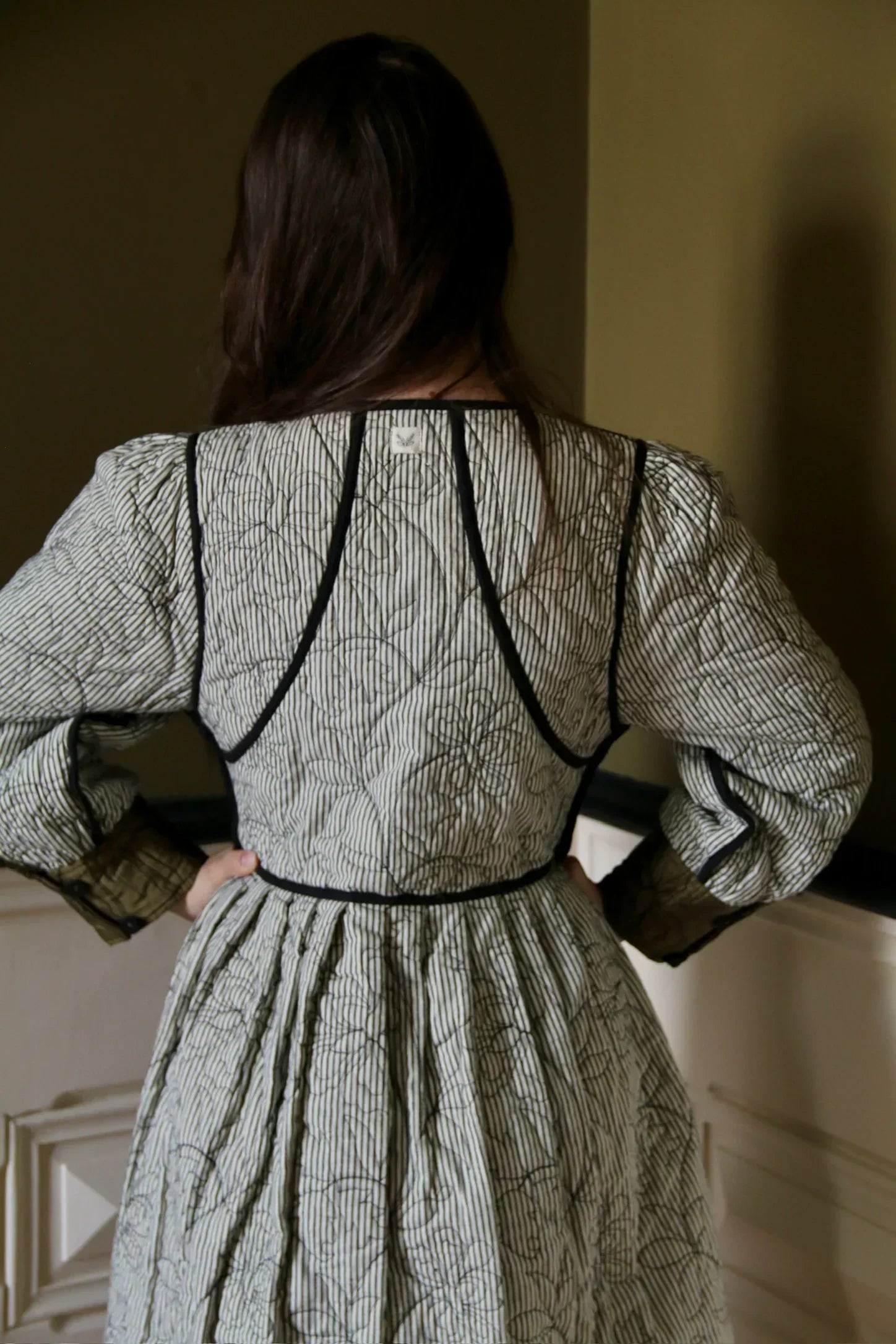 Back view of woman in a long-sleeve quilted dress with striped and floral pattern