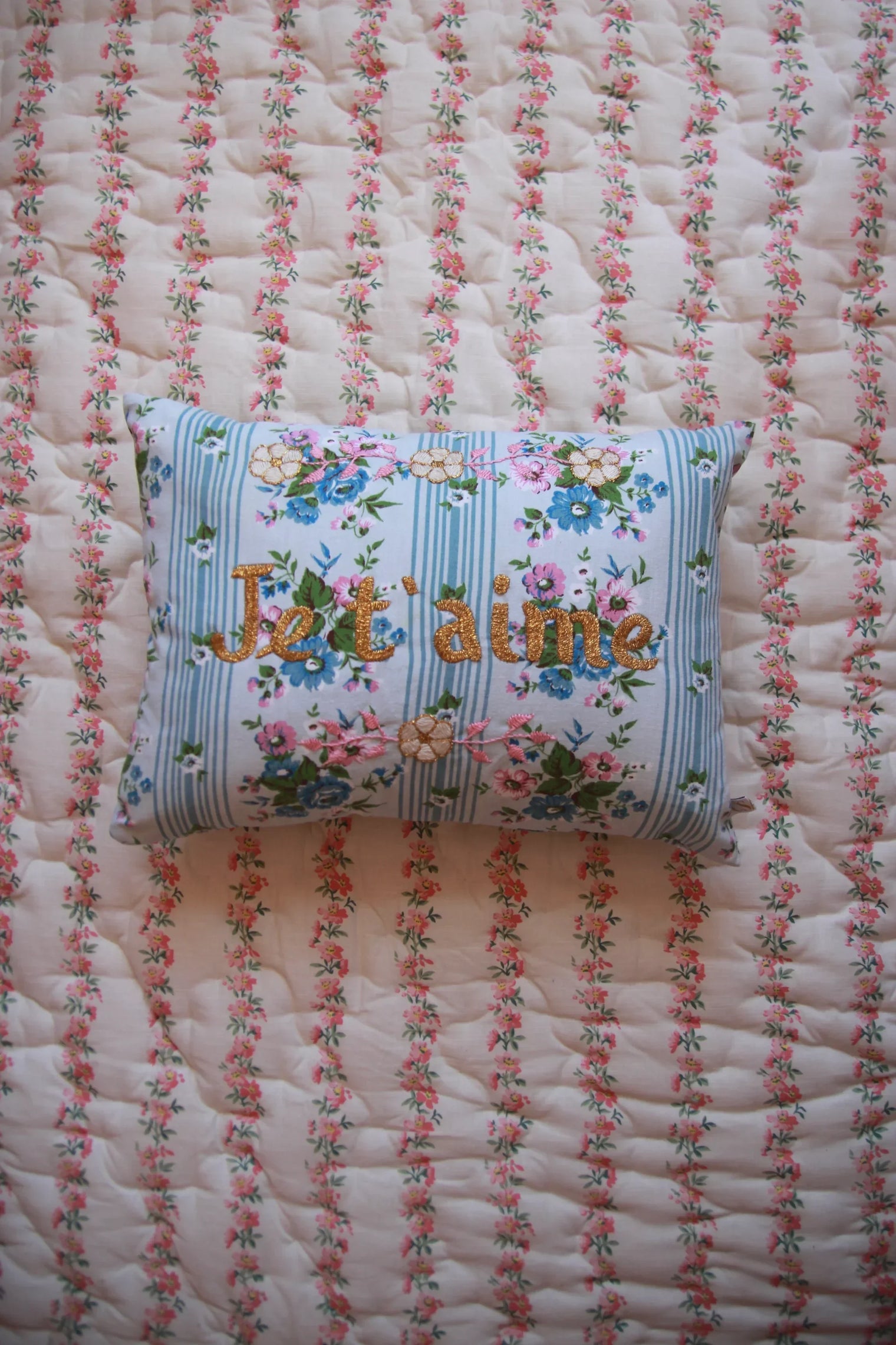 Floral embroidered cushion with 'I love you' on a quilted floral bedspread
