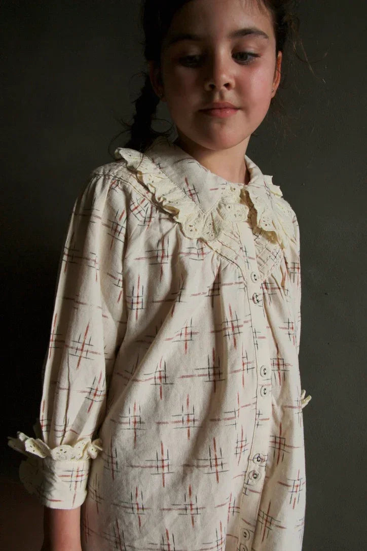 Girl wearing cream plaid button-down dress with lace collar and sleeve accents