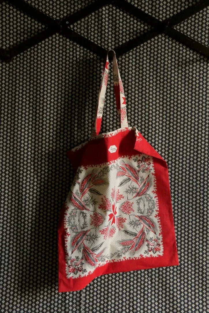 Red and white floral print cotton tote bag hanging on patterned wall
