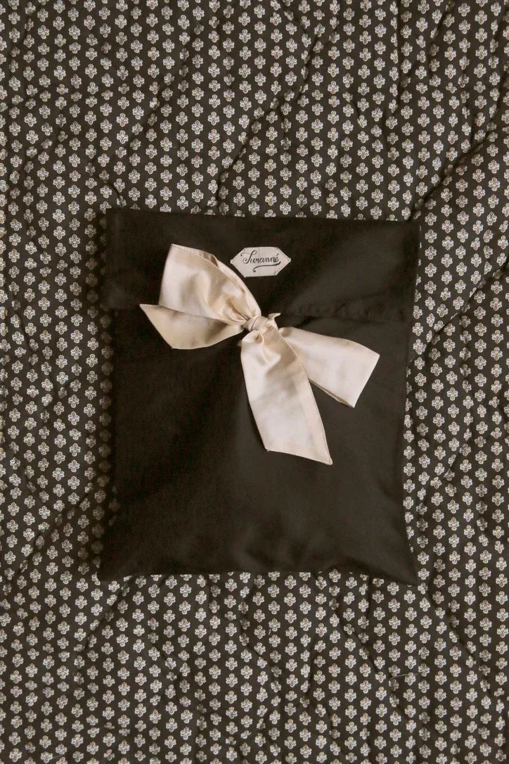 Quilted patterned bedding with a black fabric pouch tied with a cream bow on top