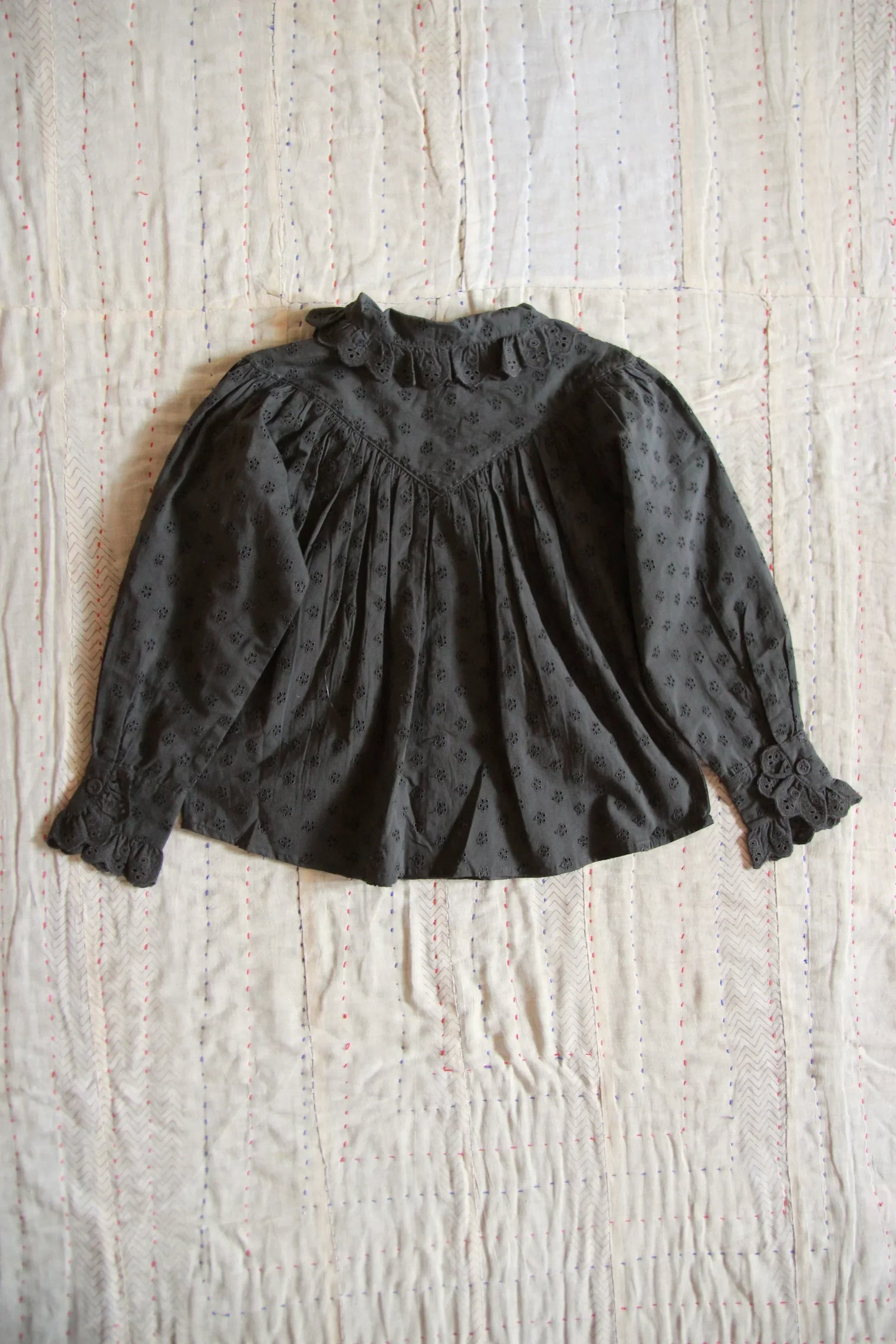 Dark floral embroidered long-sleeve girls' blouse with ruffled collar on cream quilt