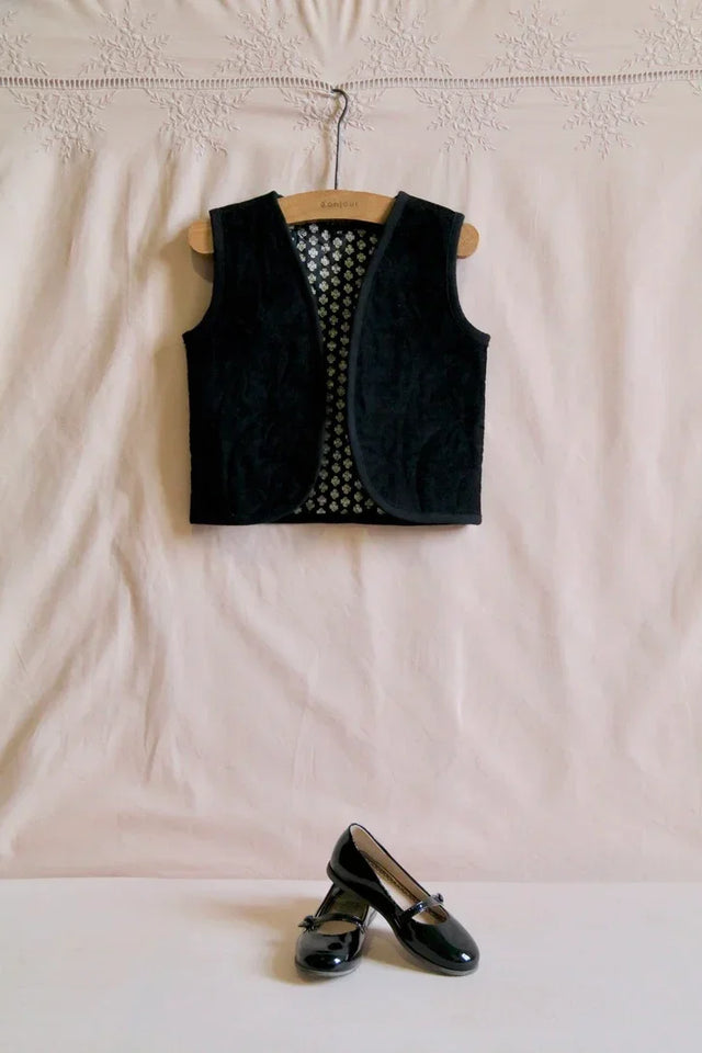 Black children's velvet vest on hanger with black patent leather ballet flats