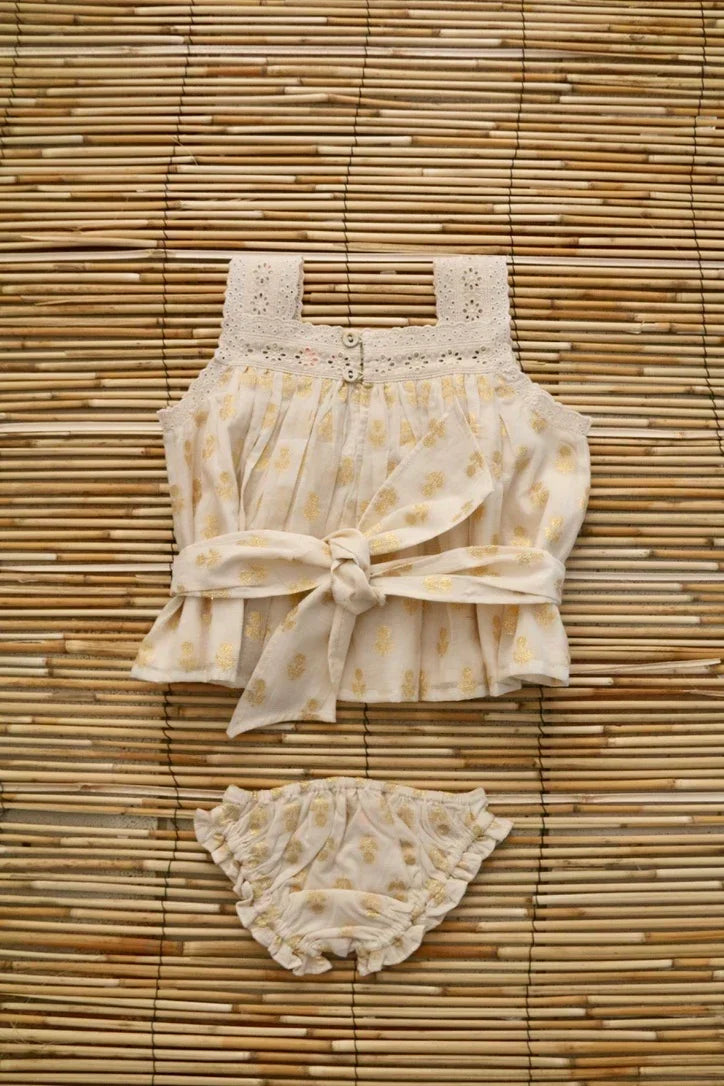 Cream floral baby top and bloomers set with lace details on woven bamboo background