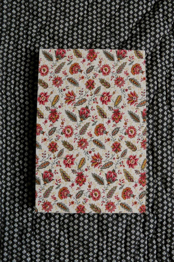 Notebook with vintage floral print cover on black and white patterned fabric background