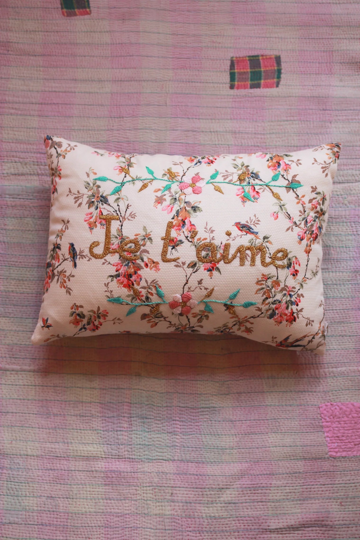 Floral embroidered pillow with "I love you" text on pink patterned quilt