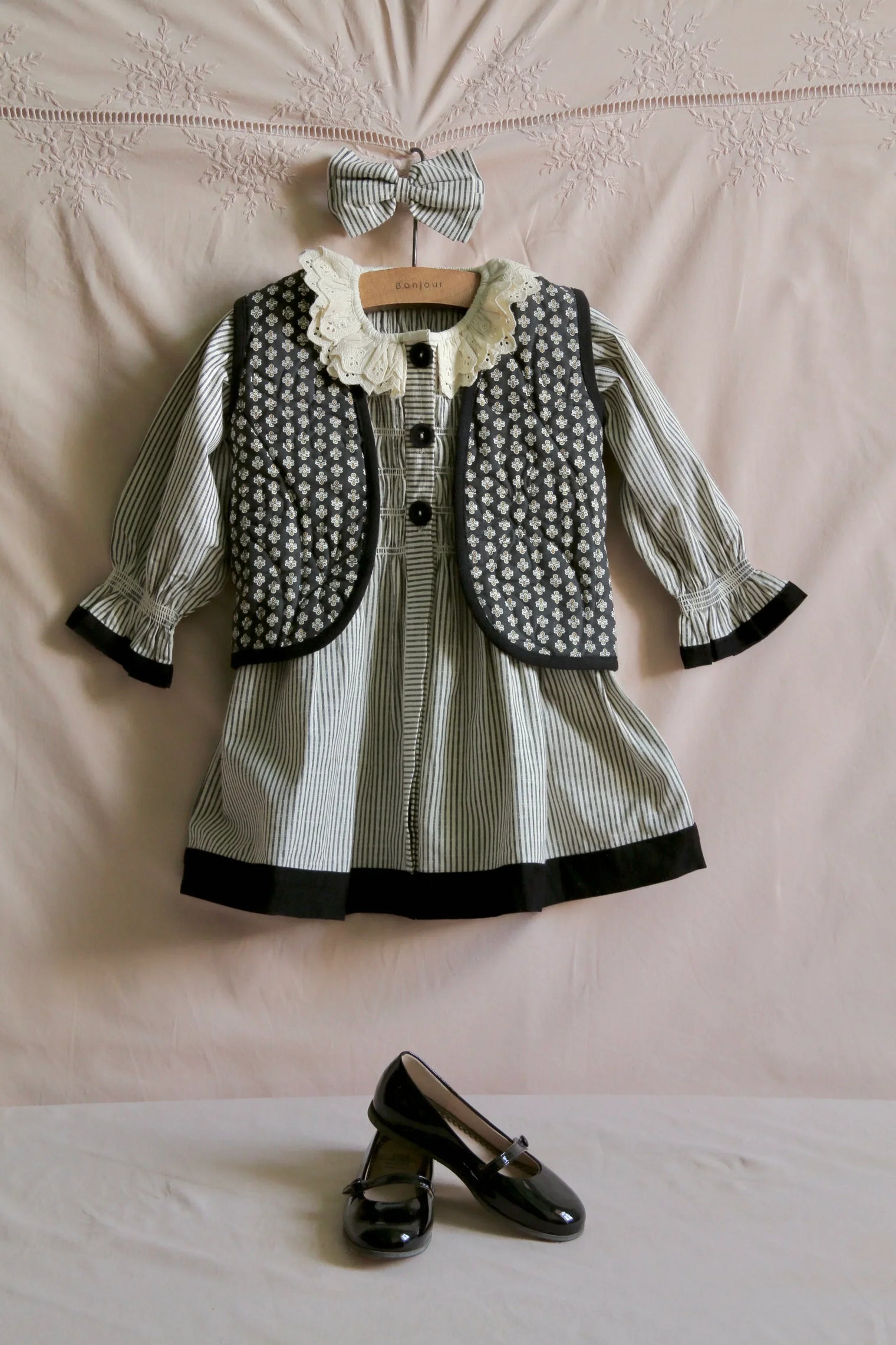 Striped children's dress set with floral quilted vest, matching bow, and black Mary Jane shoes