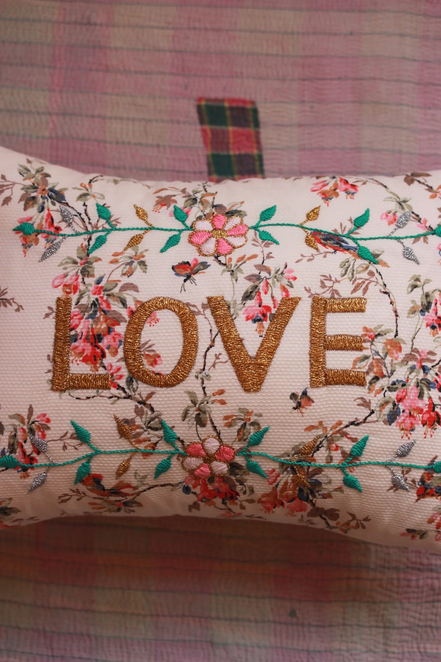 Decorative cushion with gold embroidered 'LOVE' and floral design on a quilted background