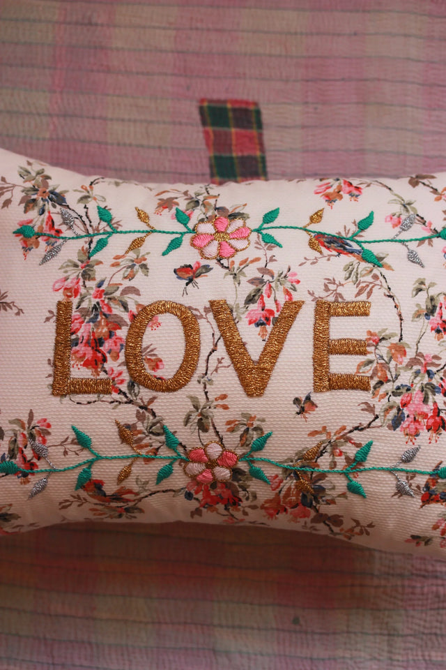 Decorative cushion with gold embroidered 'LOVE' and floral design on a quilted background