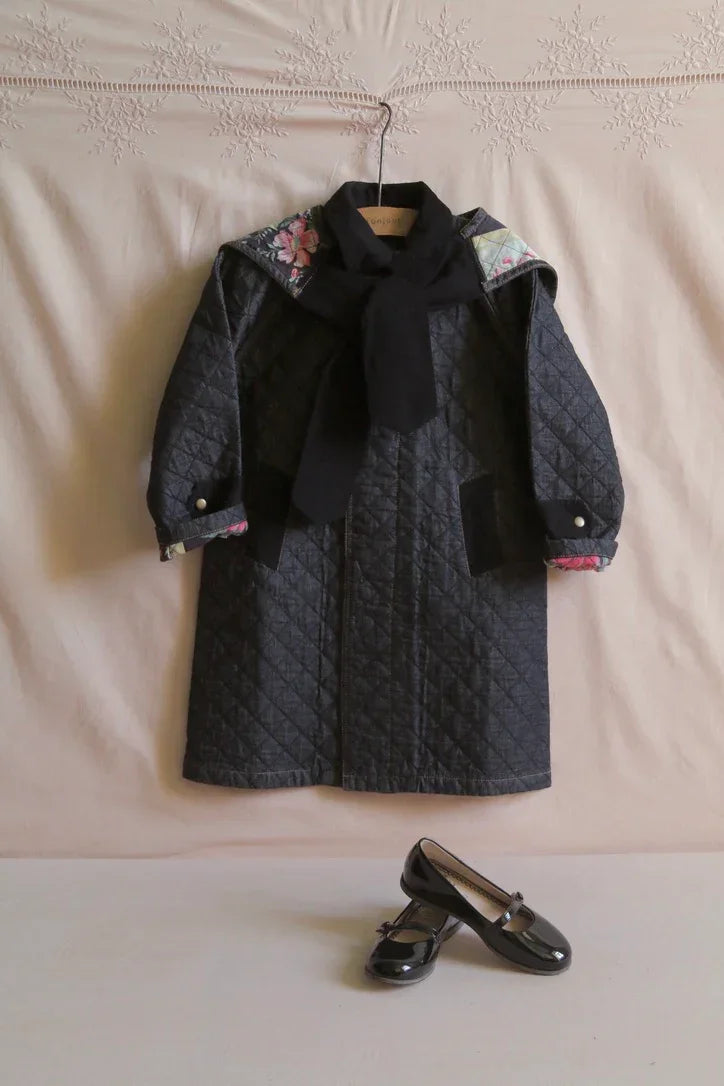 Quilted black children's coat with floral accents, matching black scarf, and black Mary Jane shoes