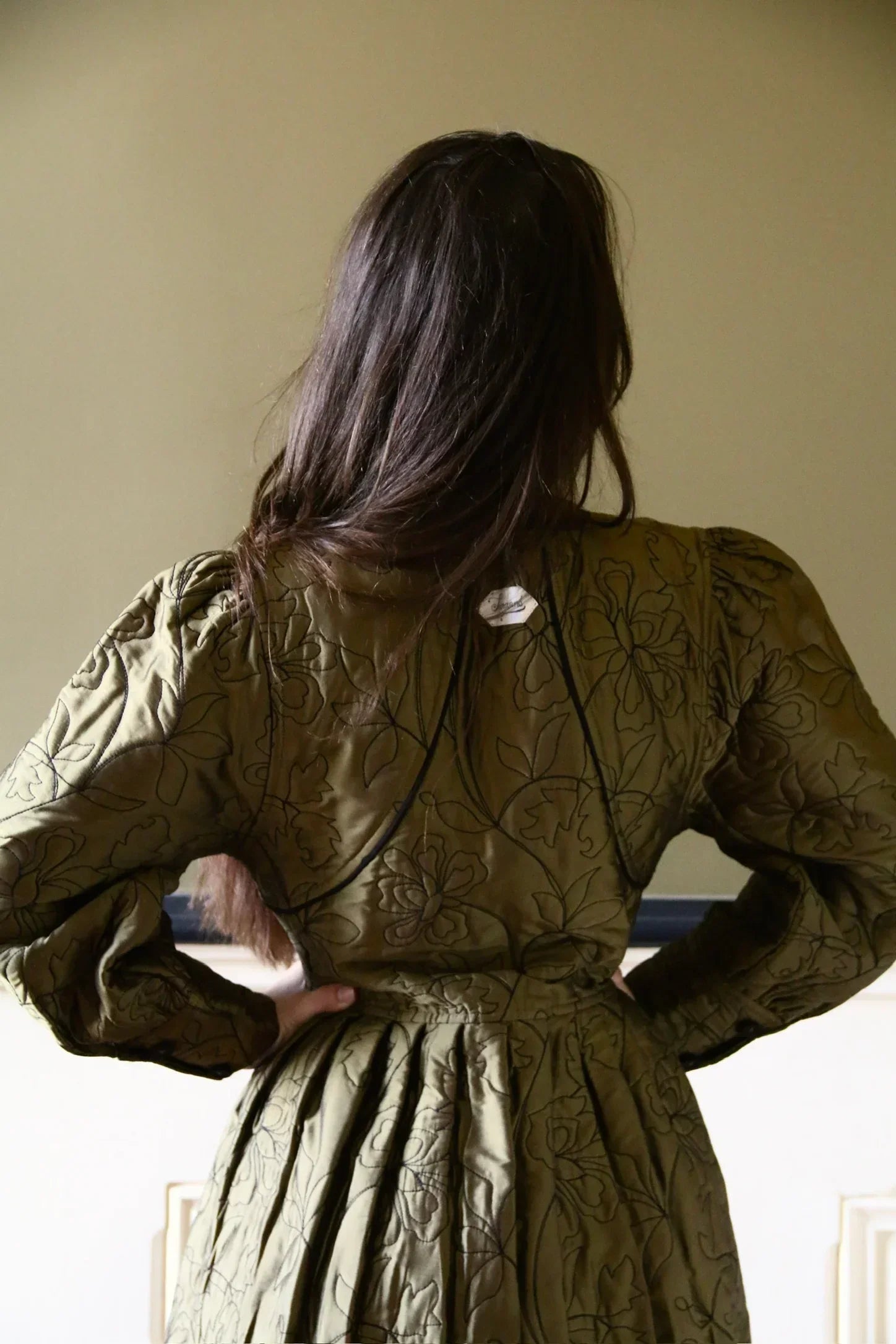 Woman wearing green embroidered floral dress with puffed sleeves, shown from the back