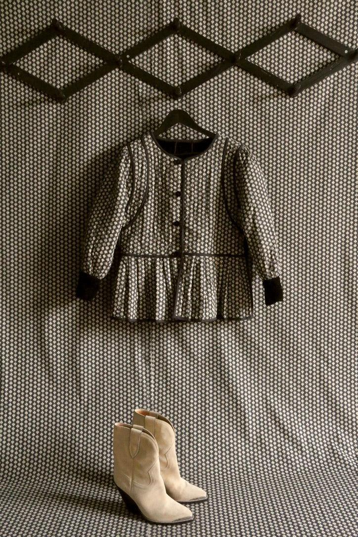 Patterned children’s dress with long sleeves and beige boots on matching fabric background