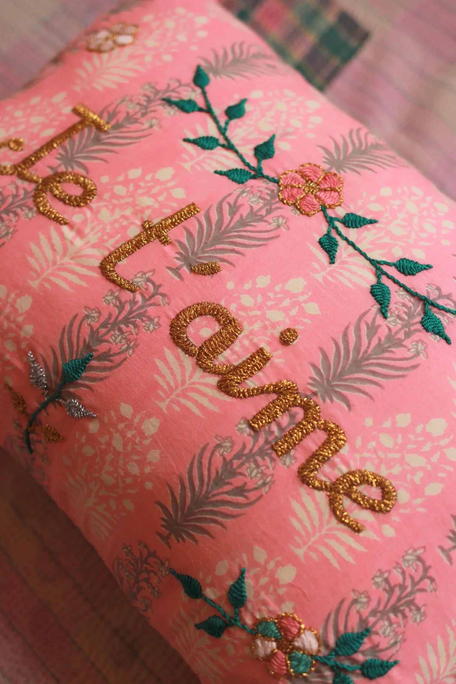 Pink decorative pillow with gold embroidered 'je t’aime,' floral print, and colorful flower accents