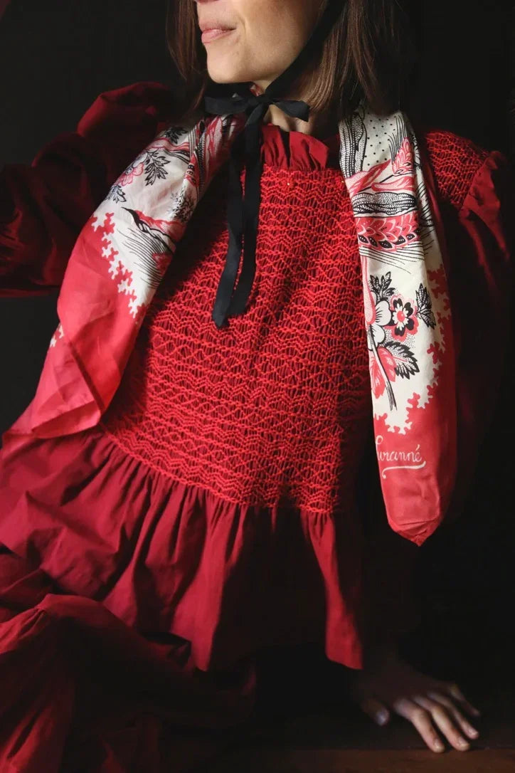 Woman in red smocked dress with ruffled collar and printed silk scarf, elegant fashion