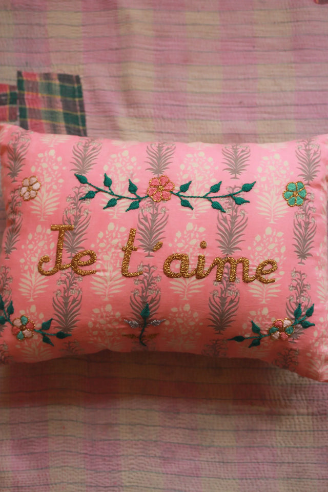 Pink embroidered floral pillow with 'I love you' text on patterned linen fabric
