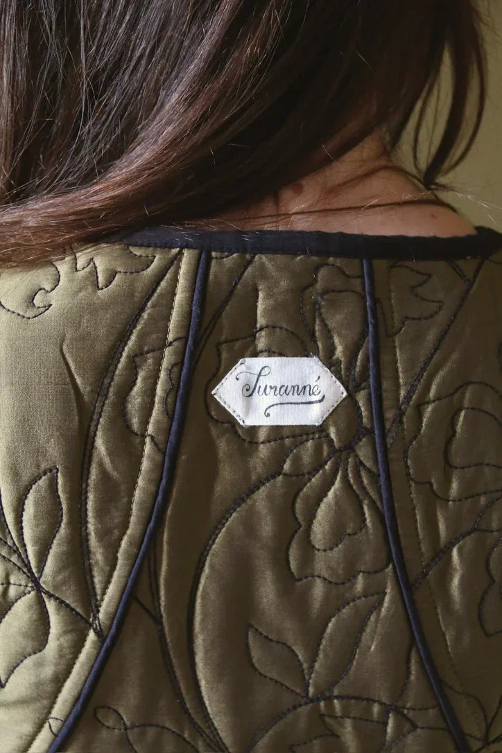 Back view of a quilted olive green garment with floral stitching and Suranné label