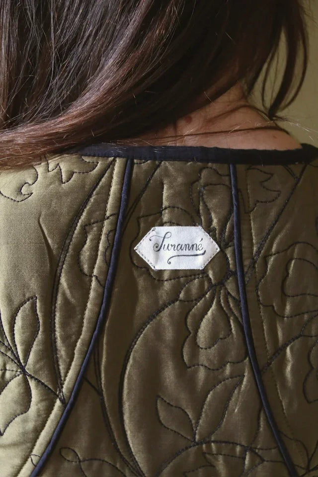 Back view of a quilted olive green garment with floral stitching and Suranné label