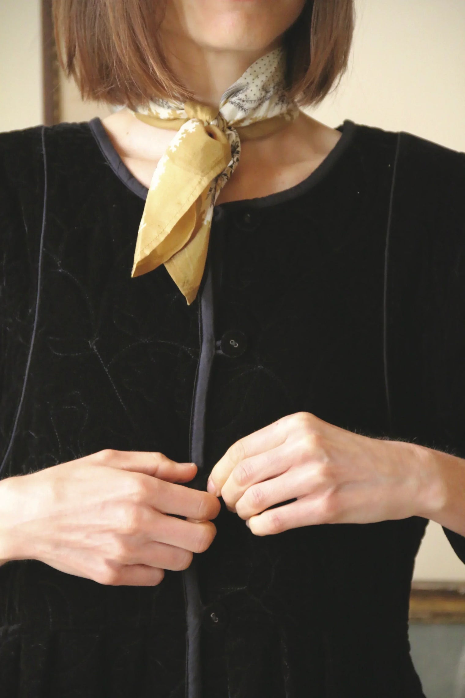 Woman in black buttoned velvet top with yellow patterned neck scarf