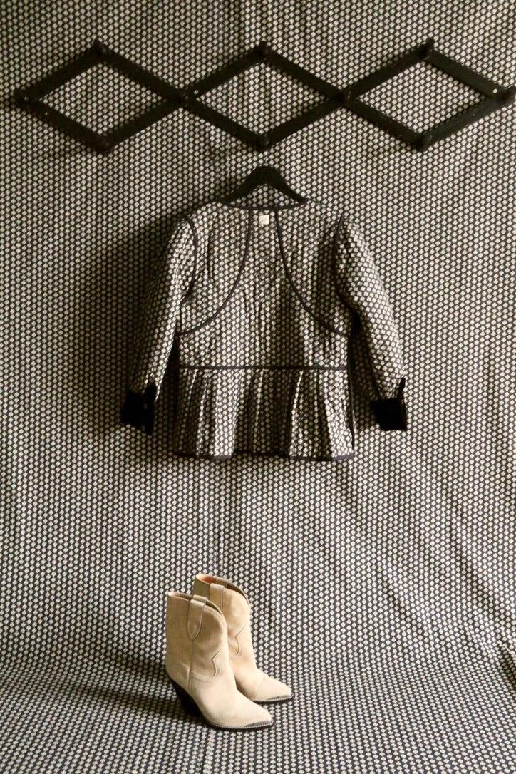 Children's patterned jacket on hanger and cream boots against geometric print background