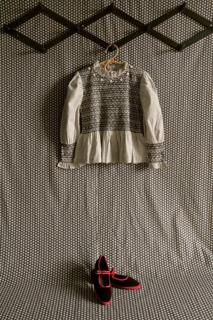 Striped long-sleeve children’s blouse with ruffle hem and black velvet Mary Jane shoes