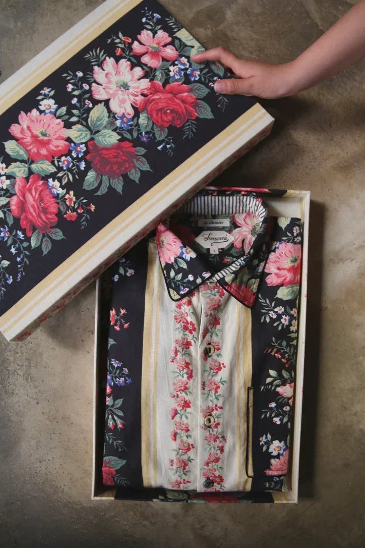Floral print shirt neatly folded in a floral gift box with hand opening the lid.