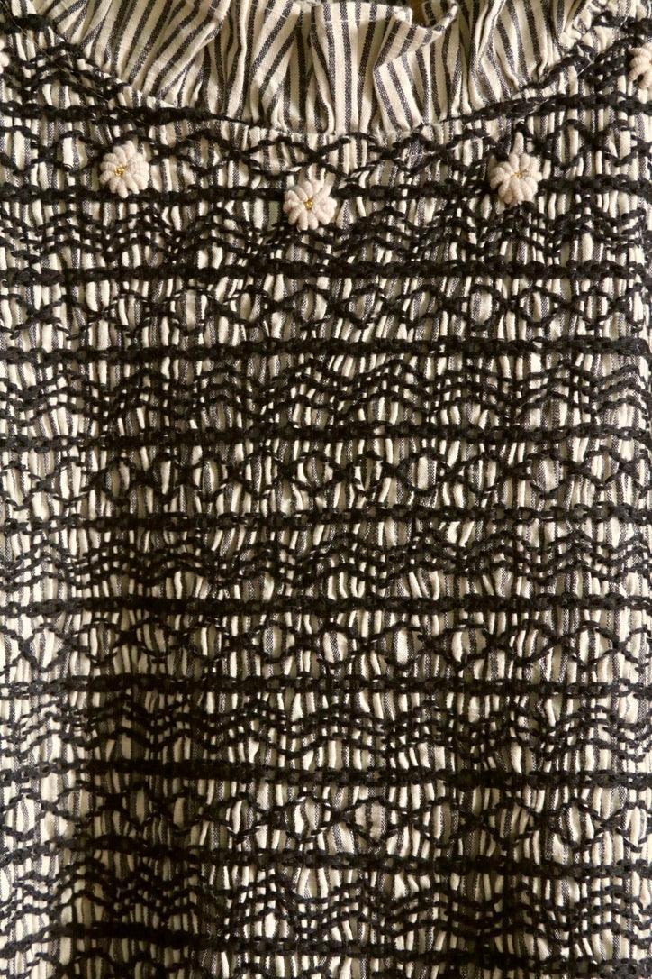 Striped fabric with hand-embroidered smocking and small floral details, close-up view