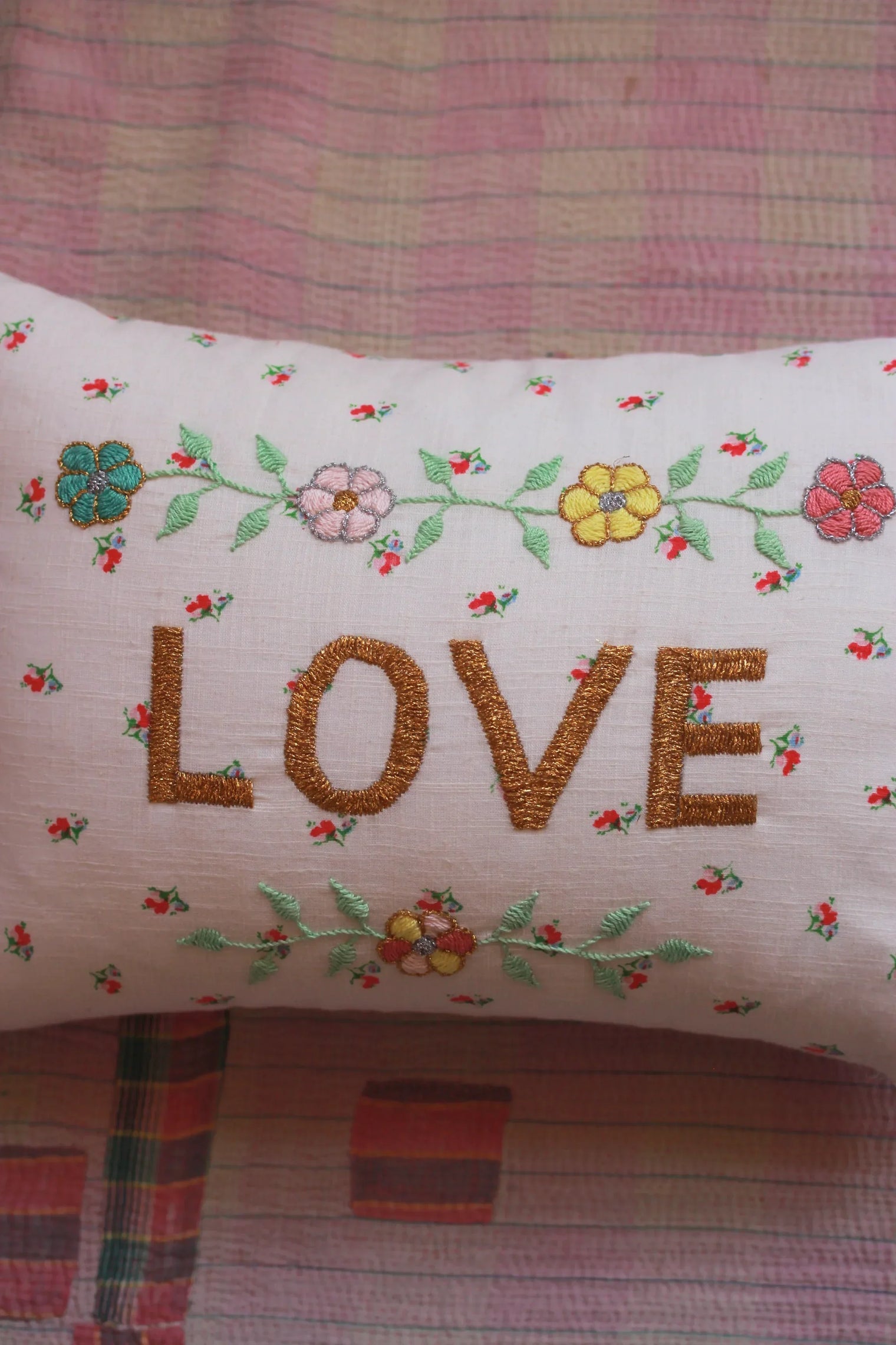Embroidered floral linen cushion with the word LOVE, pink quilt background, home decor