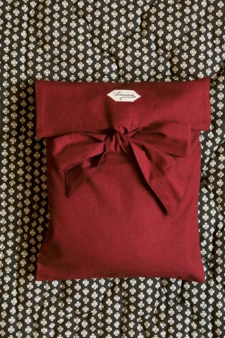 Burgundy fabric pouch with a bow on a floral patterned quilted background