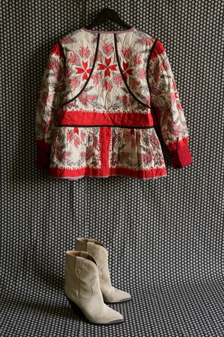Floral quilted children's jacket with red accents on hanger, beige suede boots below.