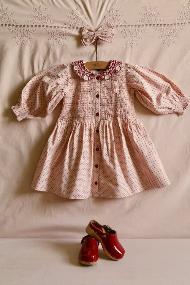 Pink polka dot girls dress with embroidered collar, matching hair bow, and red clogs