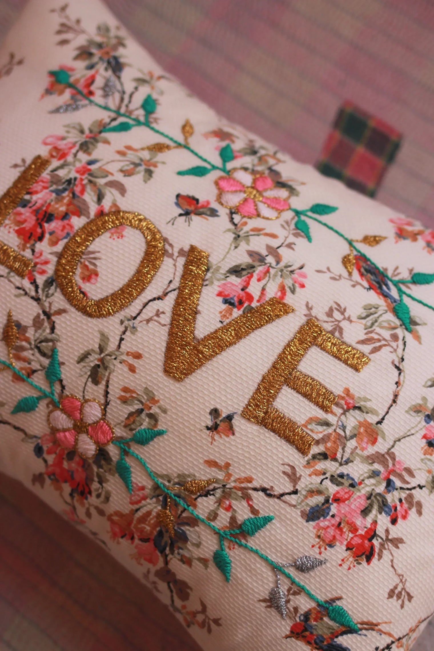 Decorative cushion with gold 'LOVE' embroidery and floral pattern on light fabric