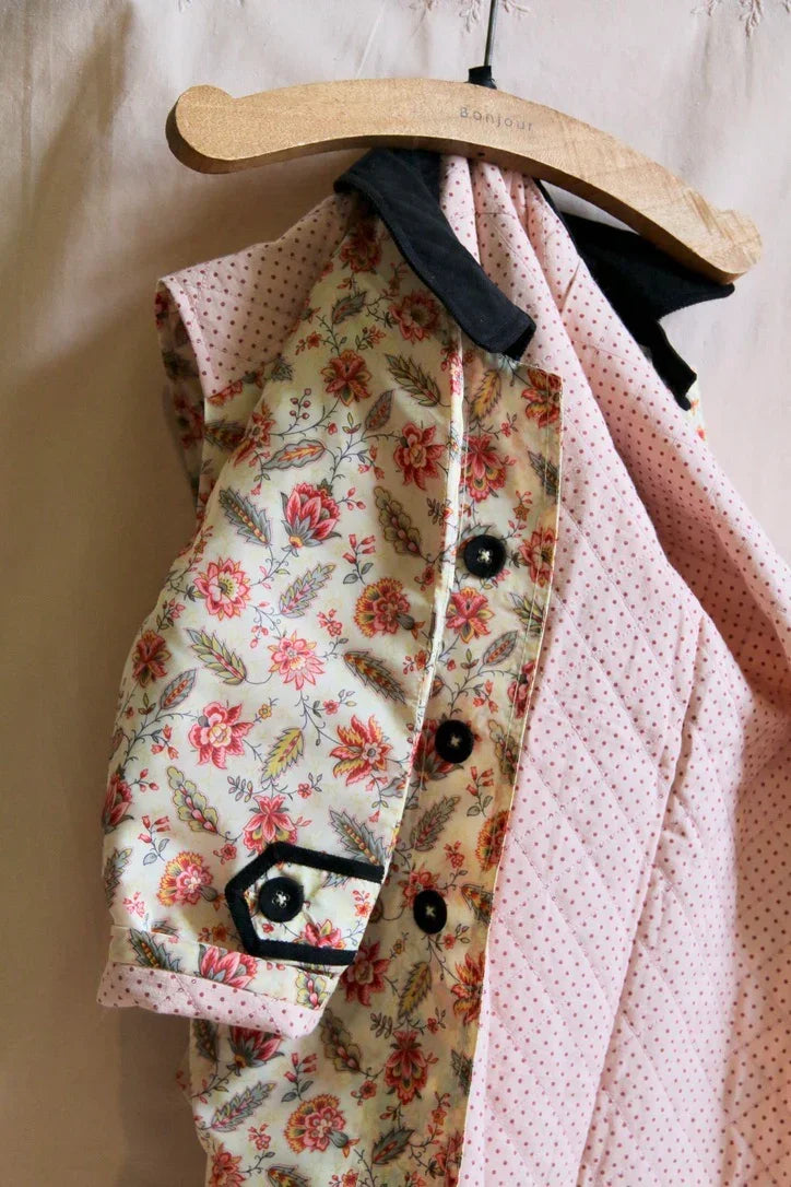 Children's floral print shirt with black buttons and contrasting collar on a hanger