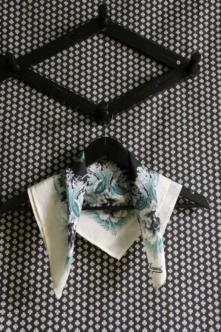 Floral print scarf on black hanger against patterned wall, home linen textile design