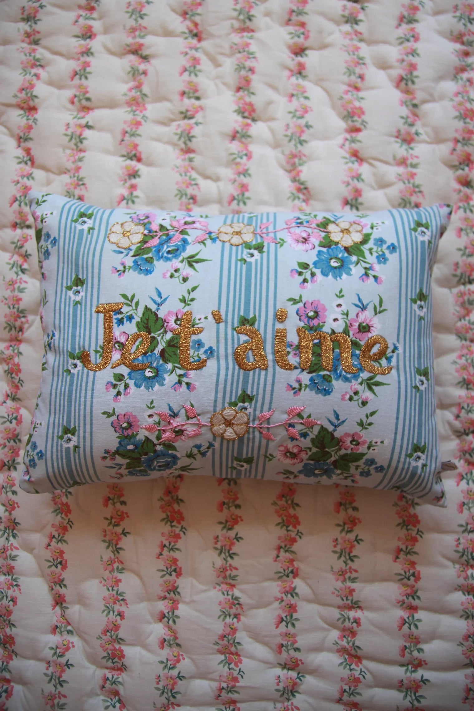 Embroidered floral cushion with I love you text on vintage stripe bedding