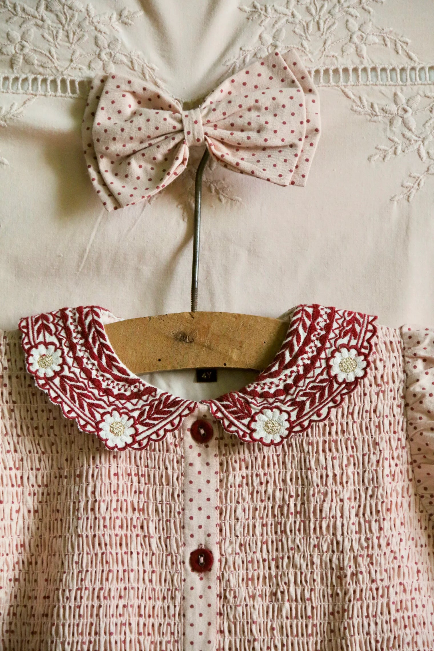 Pink polka dot smocked dress with embroidered floral collar and matching bow, kidswear