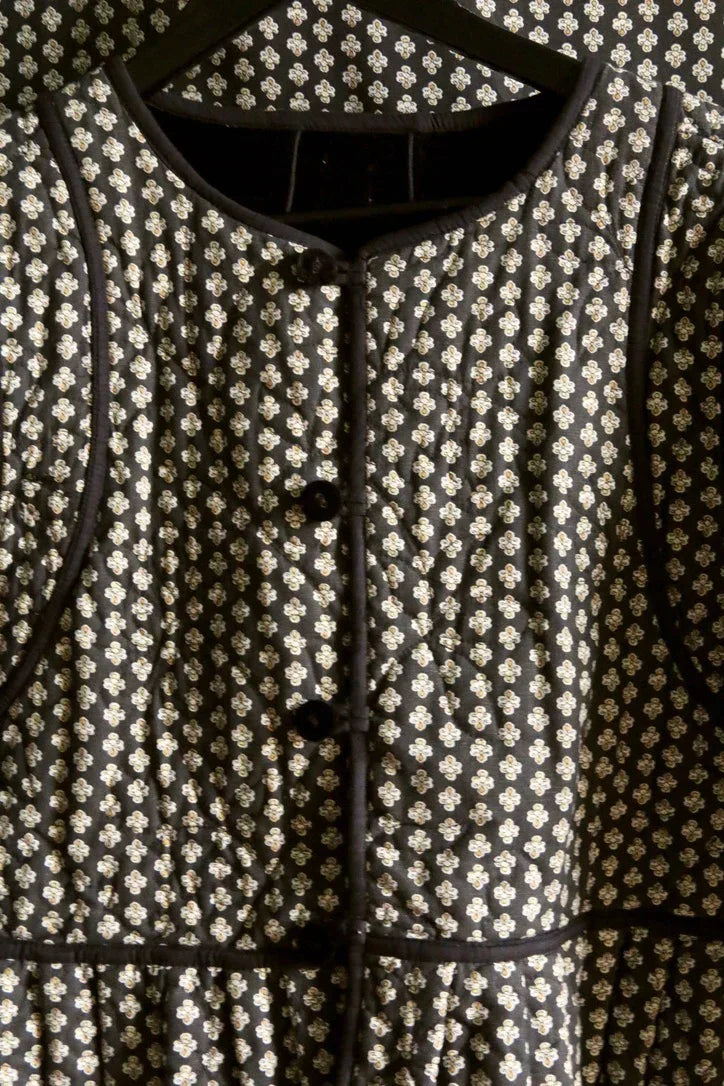 Black quilted jacket with small white floral print and black round buttons