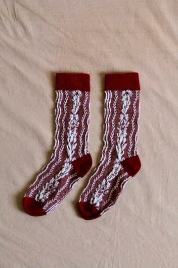 Pair of children's maroon lace socks with white floral pattern on beige background