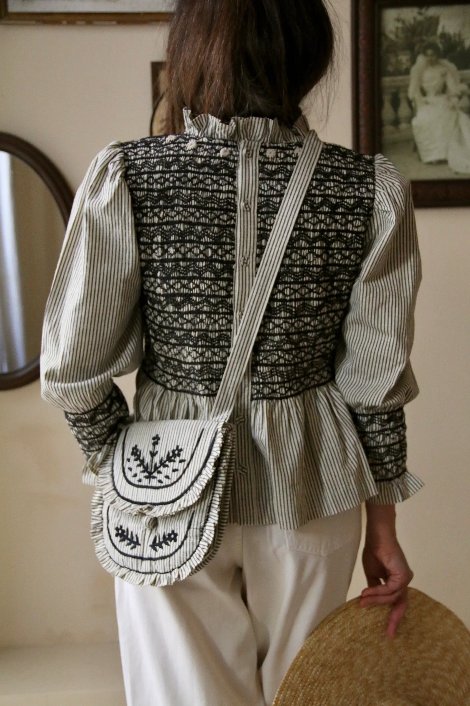 Woman wearing vintage-inspired striped blouse with embroidered smocking and matching crossbody bag