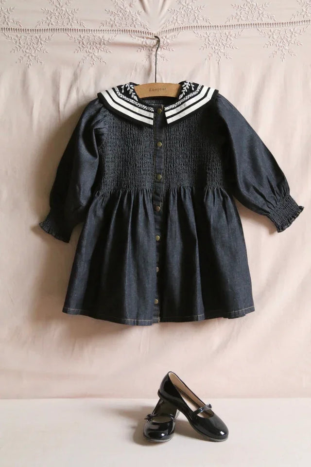 Dark blue smocked children’s dress with sailor collar and black patent shoes