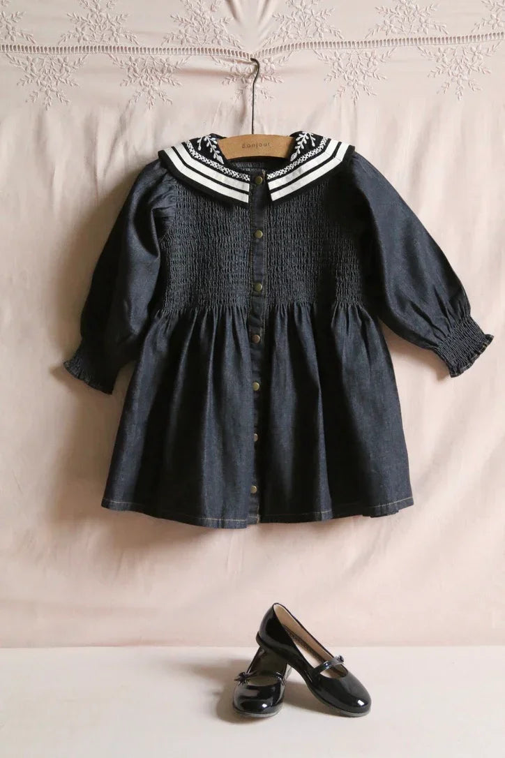 Dark blue smocked children’s dress with sailor collar and black patent shoes