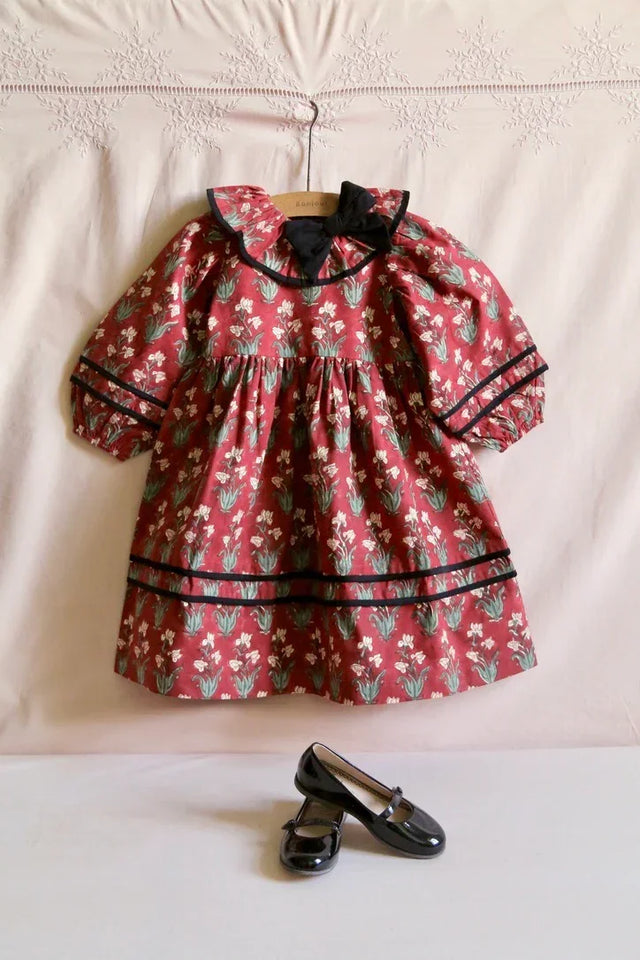 Red floral long-sleeve girls dress with black trim, paired with black Mary Jane shoes