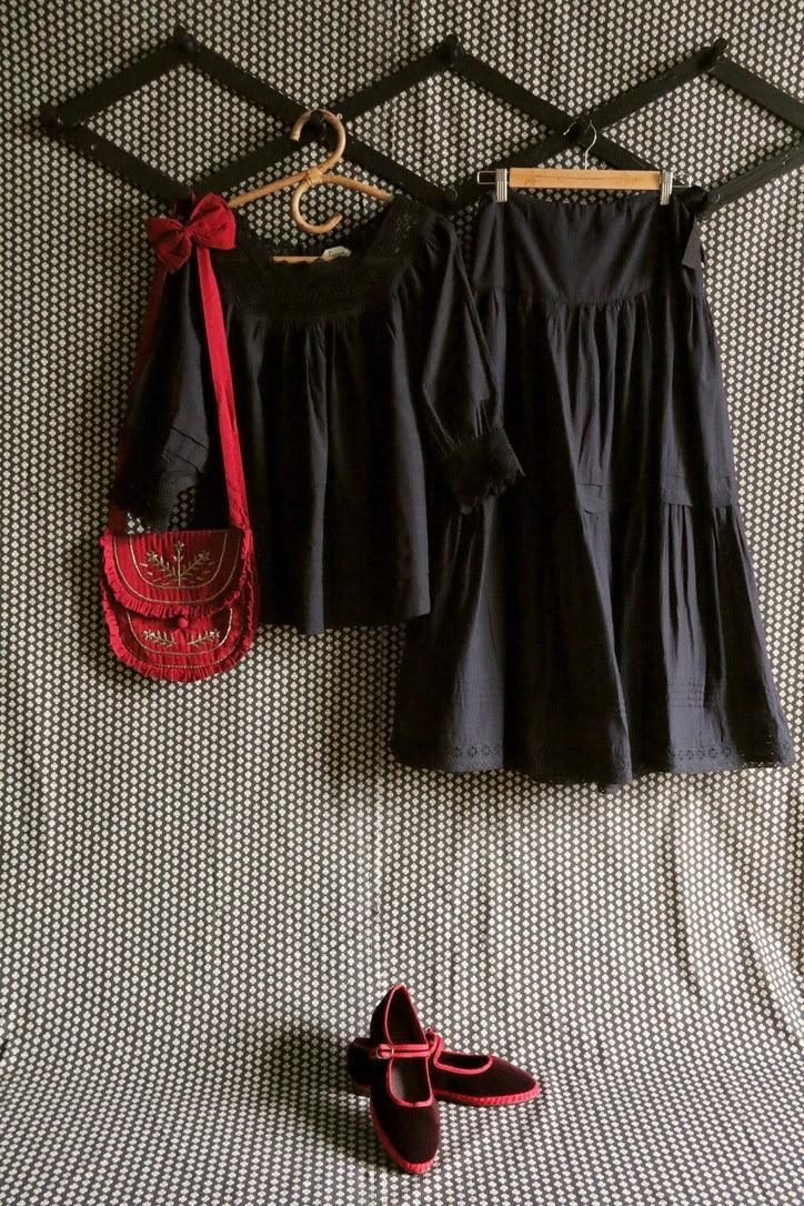 Black children's dress and skirt set with red embroidered bag and matching red-trimmed shoes