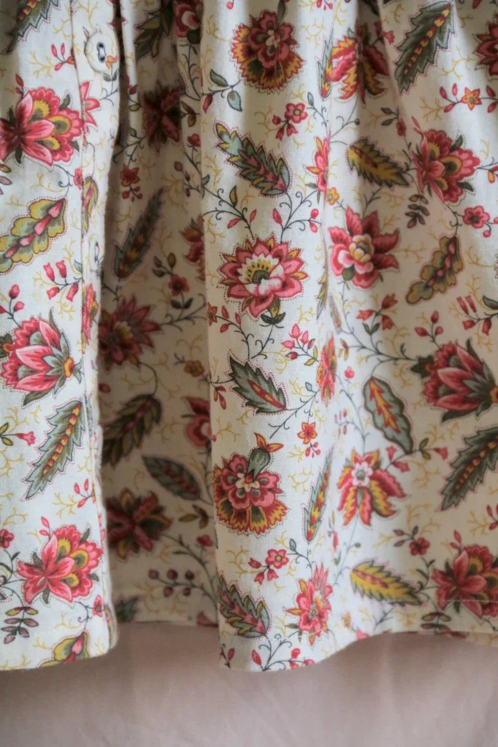 Close-up of fabric with pink floral print and green leaves, vintage-inspired childrenswear textile