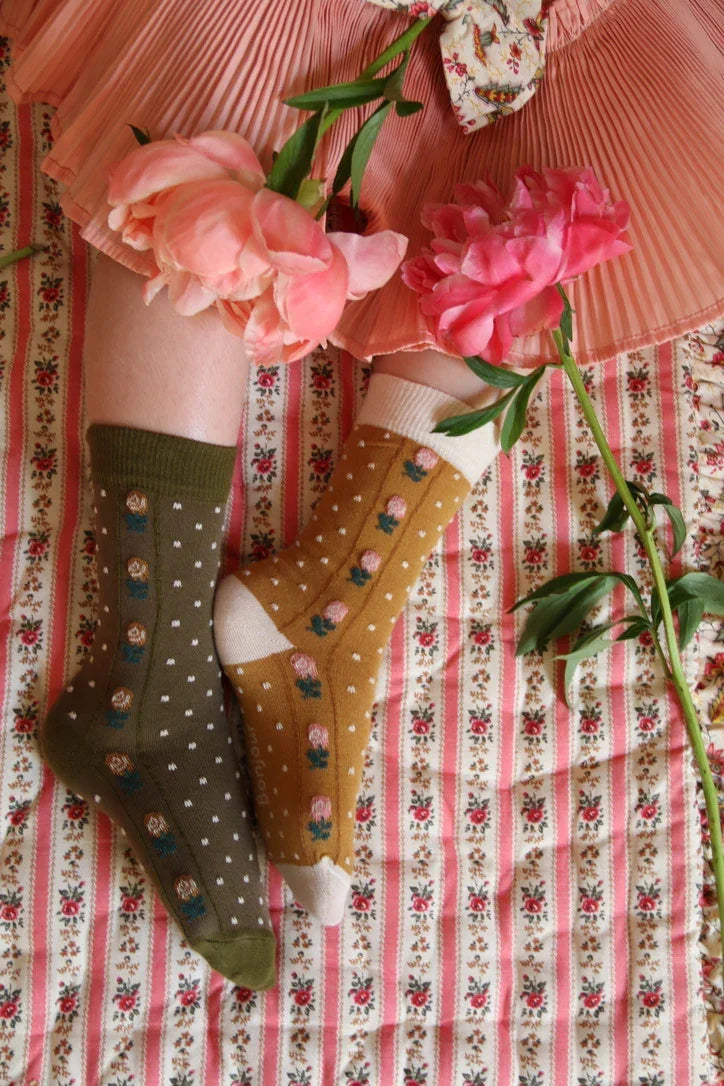 Children’s patterned socks with floral designs, pink skirt, and peonies on vintage floral fabric