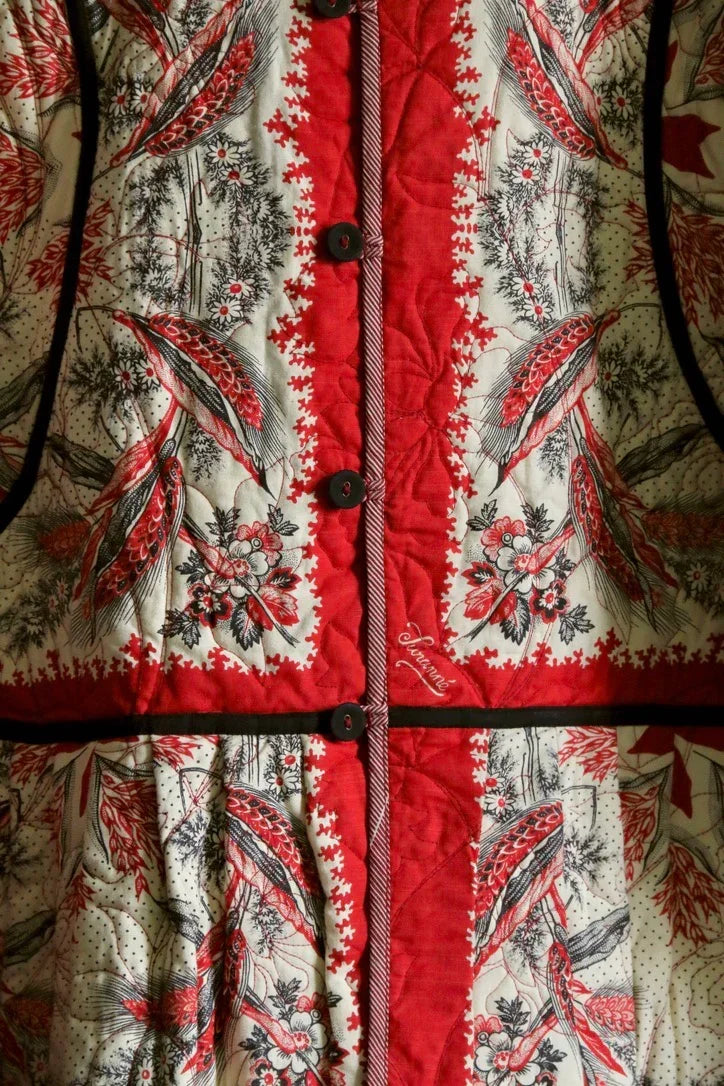 Close-up of a quilted dress or jacket in red and cream with bird and floral print, buttoned front