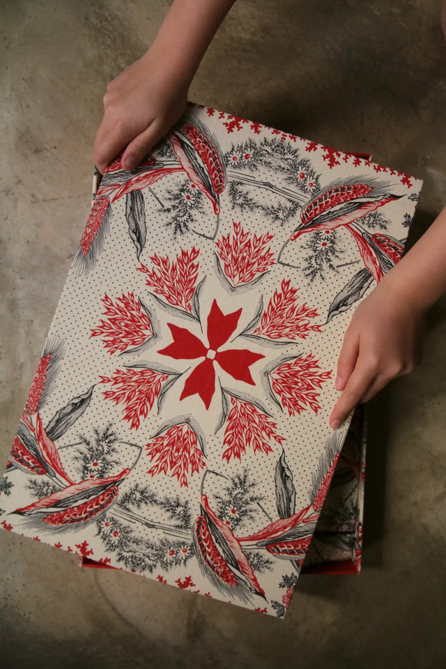 Hands holding a folder with red and black floral botanical print on beige background