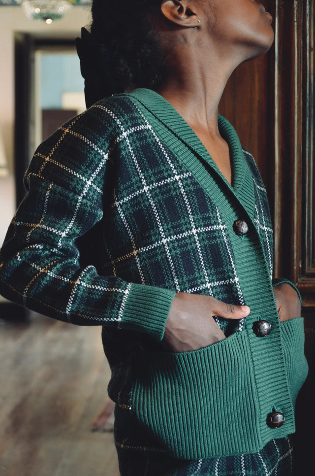 Child wearing green plaid knit cardigan with large buttons in vintage-inspired room