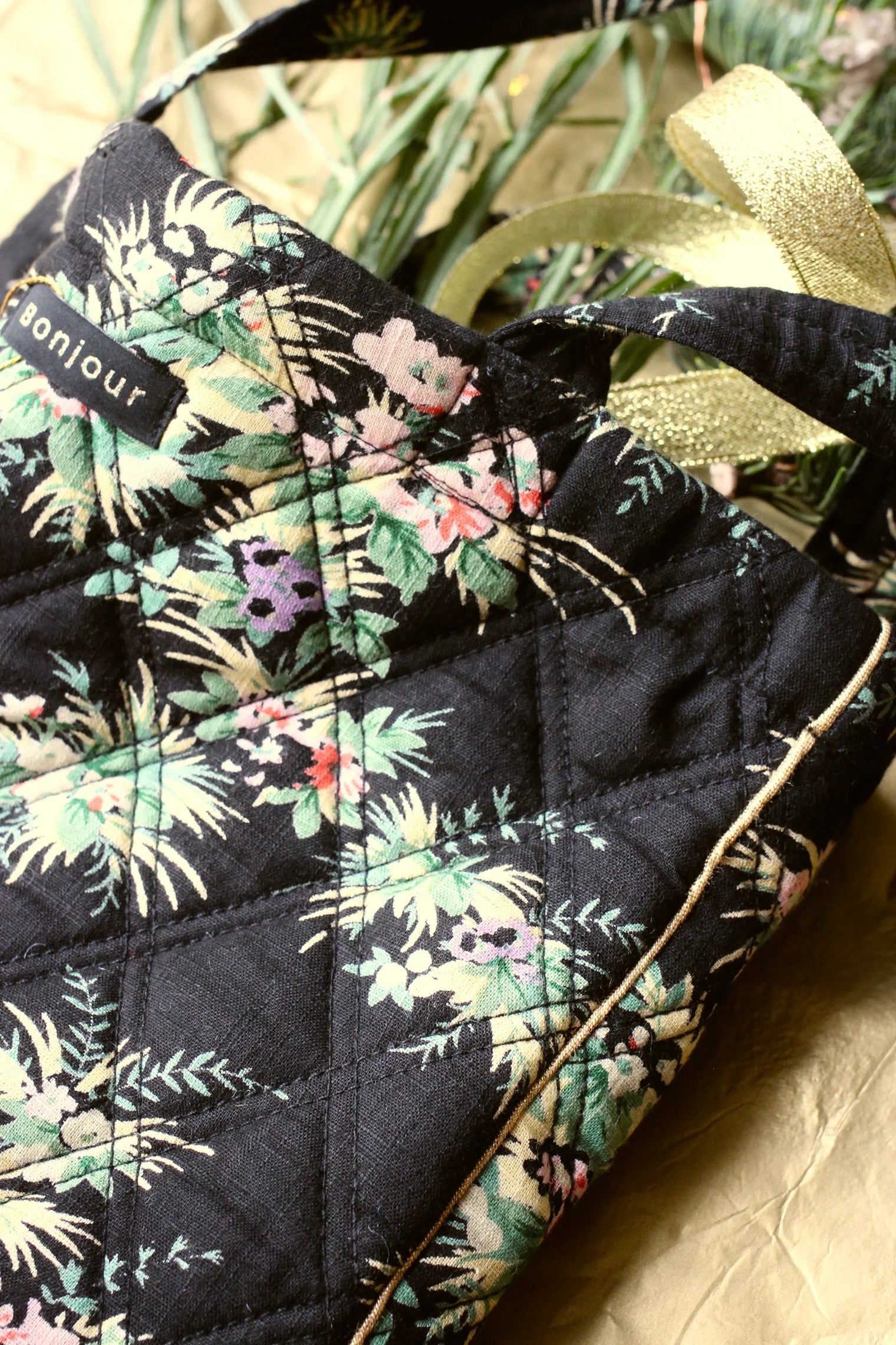 Quilted floral tote bag in dark fabric with multicolor vintage-style print and gold trim