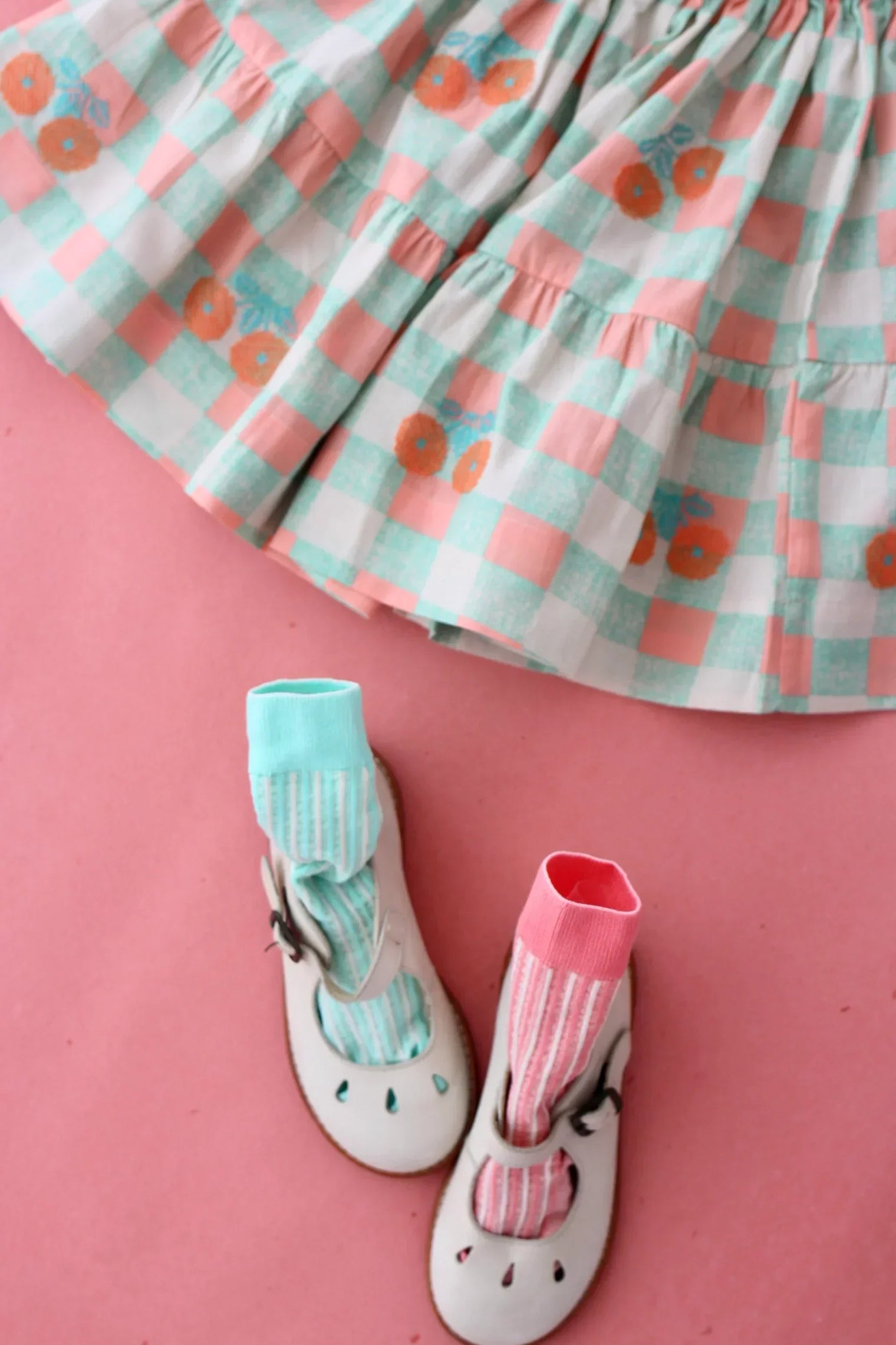Pink and mint checkered girls skirt with orange floral prints, white shoes, striped socks